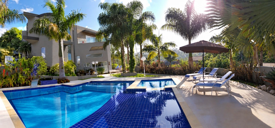 Piscina e fachada da casa entre palmeiras, vistas da área de descanso